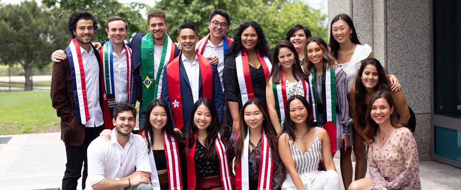 A group of students with flag sashes standing together and posing for the camera after a successful graduation brunch.